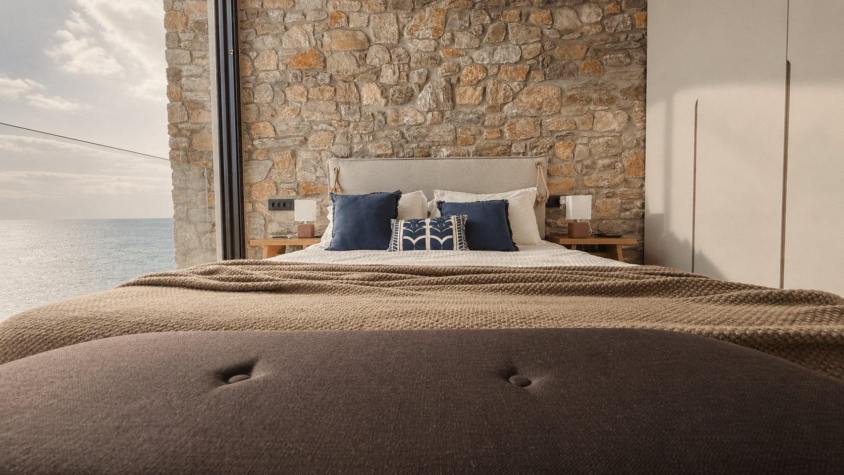 Bedroom with stone wall and dressed bed