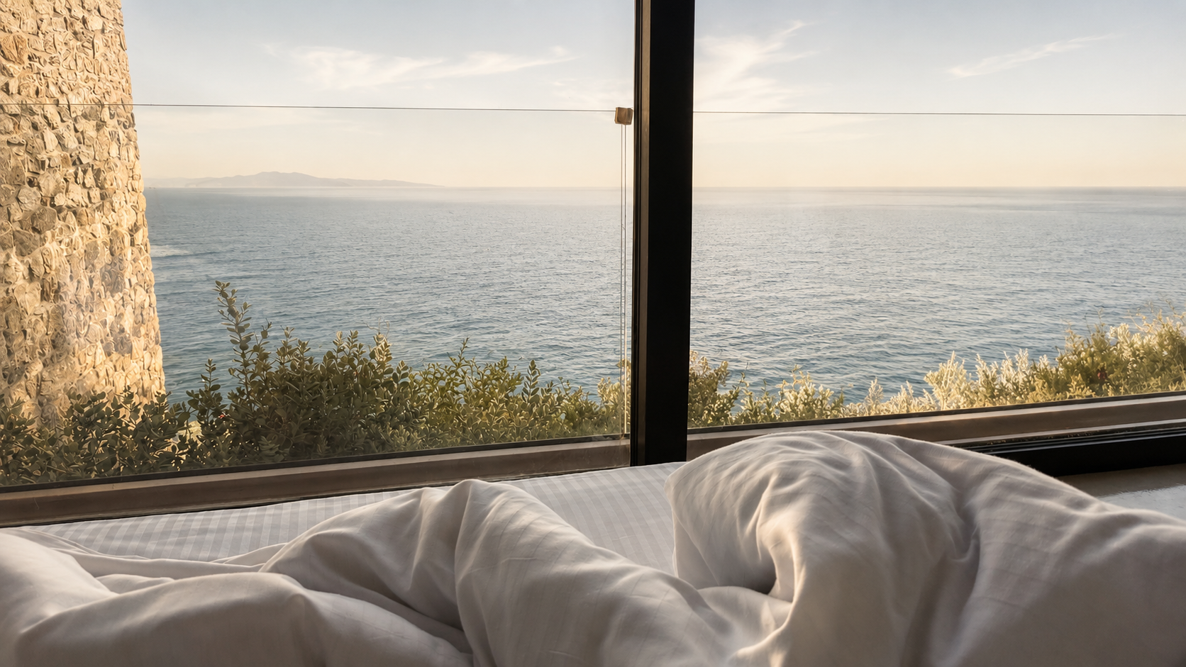 Bed framed against the sea horizon in the Nyx bedroom